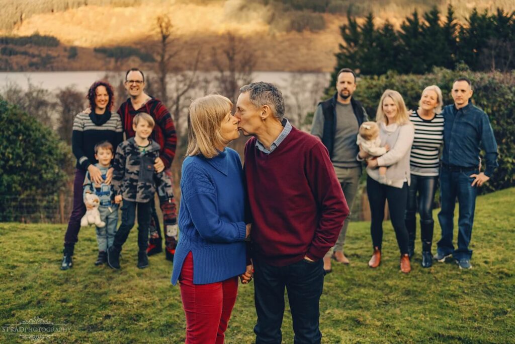 Couple in front of family gathering.