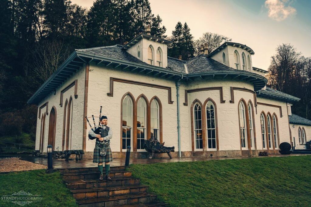 Scottish piper outside grand estate.