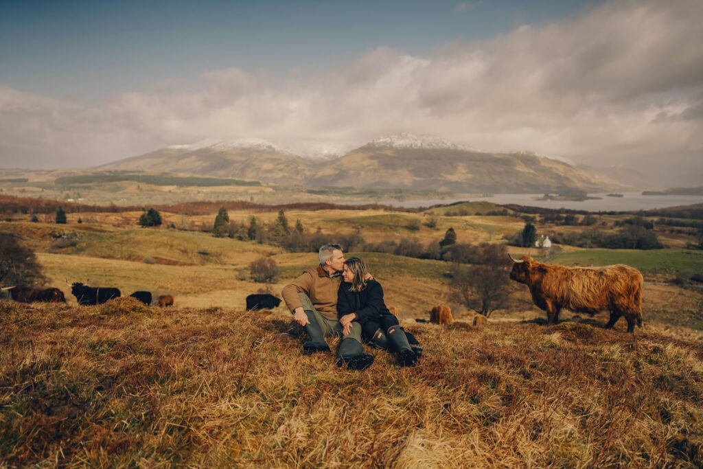 highland cow photoshoot Scotland experience at Cladich Fold with couple and Highland cows by the loch